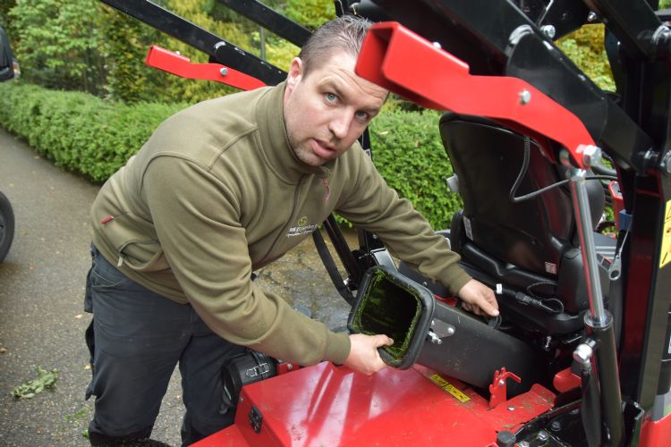 Het natte gras uit de verbindingskoker tussen maaidek en hopper halen Het natte gras uit de verbindingskoker tussen maaidek en hopper halen