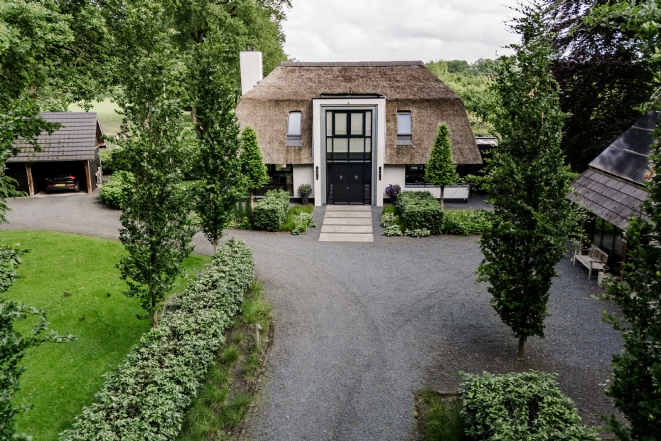 De voortuin heeft een formeel uiterlijk passend bij de statige entree van dit landhuis